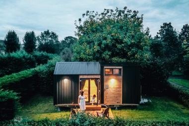 A Tiny Away house lit up at dusk in a garden in France