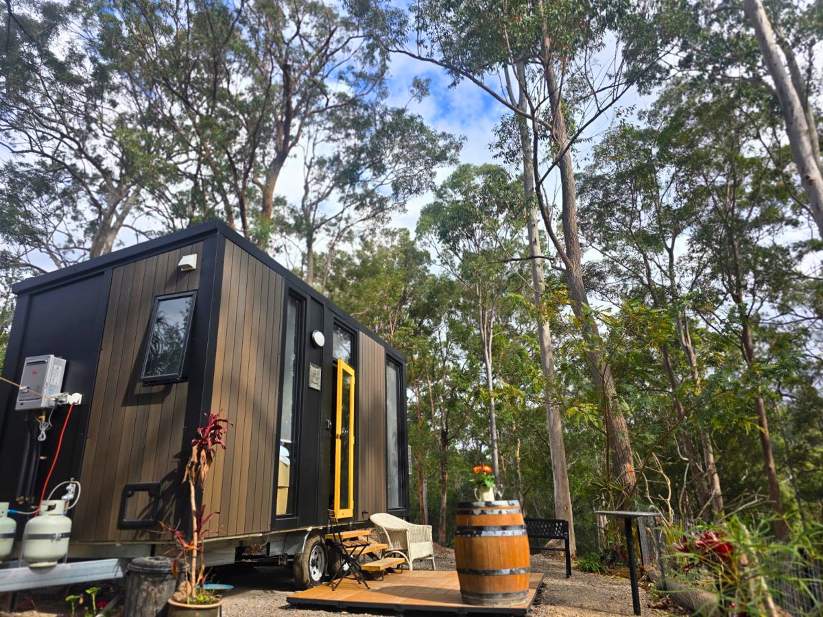 A Tiny Away house with a yellow door among tall gum trees